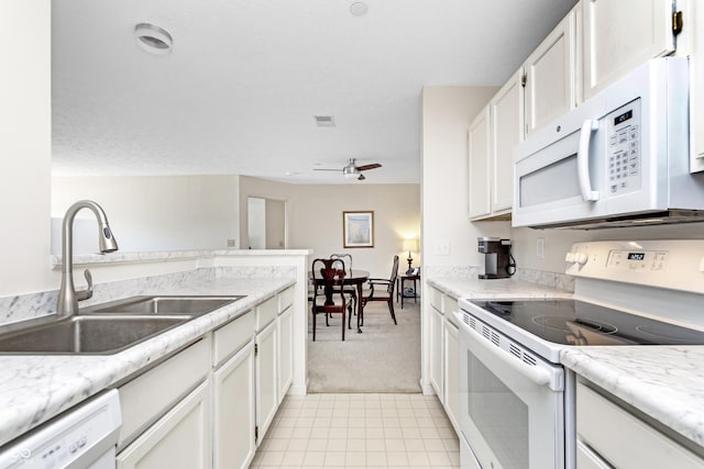 kitchen with visible vents, white appliances, white cabinetry, and a sink