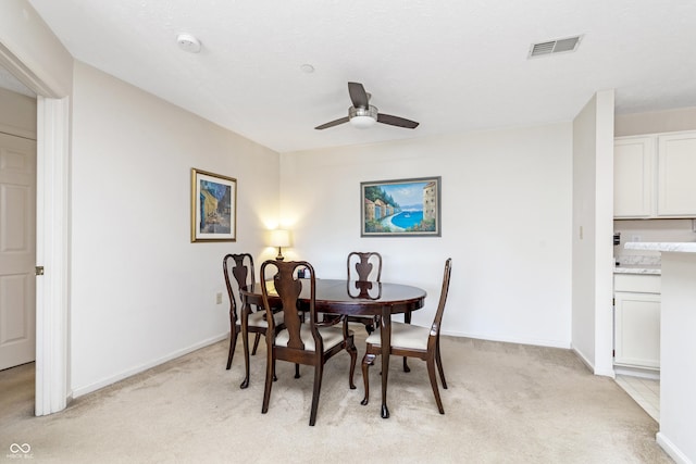 dining area featuring visible vents, light colored carpet, baseboards, and a ceiling fan