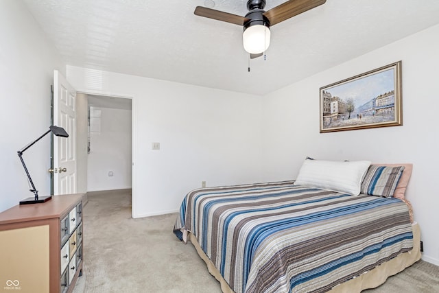 bedroom featuring light carpet, baseboards, a textured ceiling, and ceiling fan