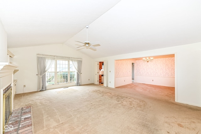 unfurnished living room with light colored carpet, a fireplace, ceiling fan with notable chandelier, and vaulted ceiling