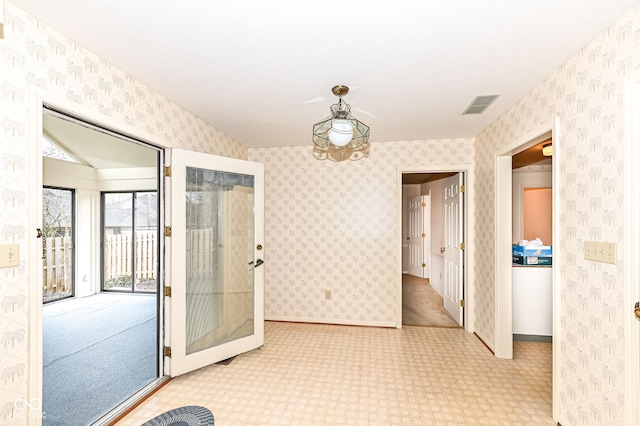 spare room with wallpapered walls, baseboards, and visible vents