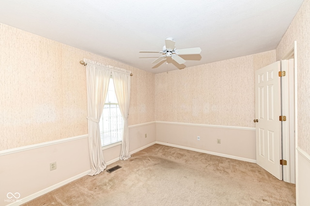 unfurnished room with wallpapered walls, ceiling fan, visible vents, and light carpet