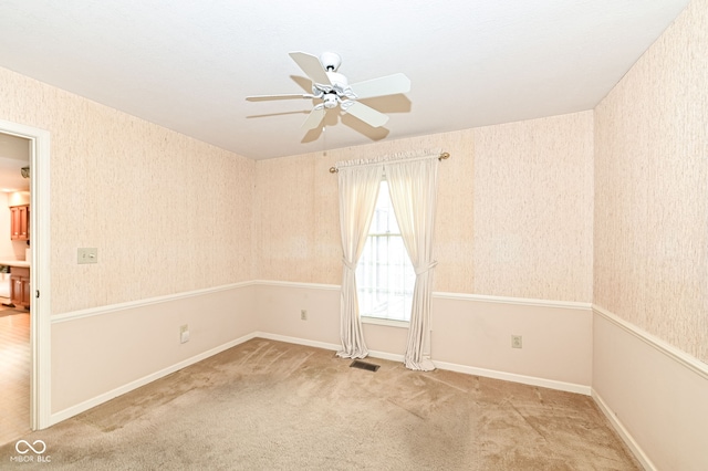 carpeted empty room with baseboards, visible vents, wallpapered walls, and a ceiling fan