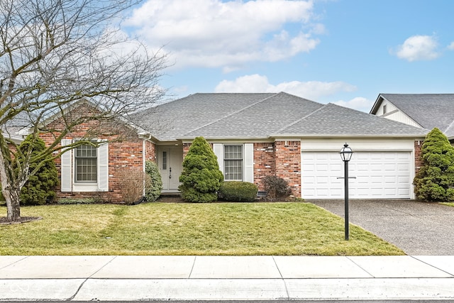 ranch-style home featuring brick siding, a shingled roof, a front yard, a garage, and driveway