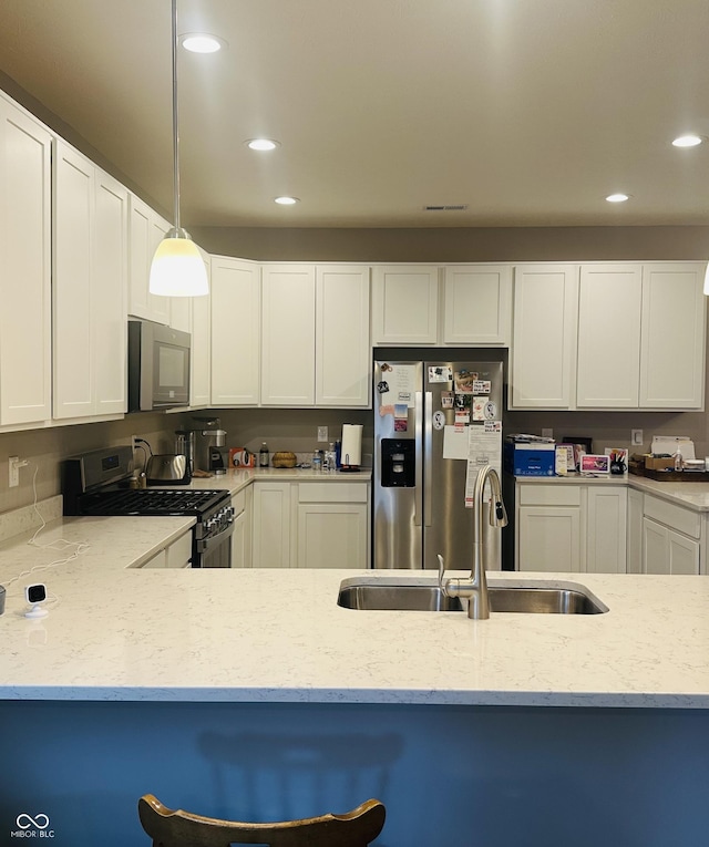 kitchen featuring a sink, light stone counters, appliances with stainless steel finishes, and recessed lighting