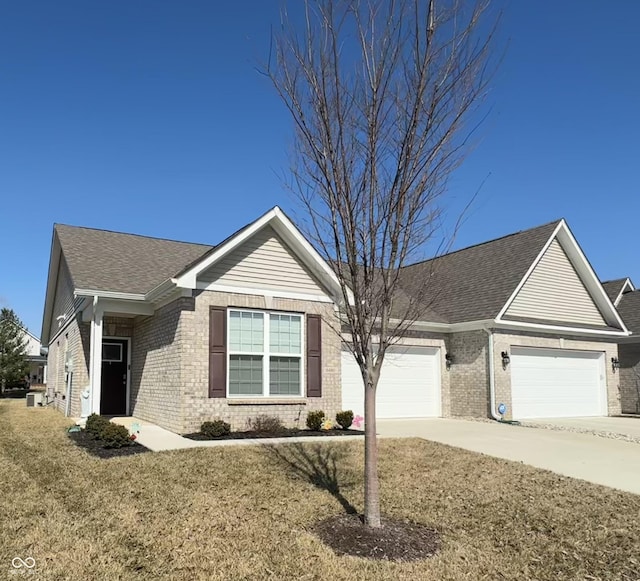 ranch-style home featuring brick siding, concrete driveway, a front yard, roof with shingles, and a garage