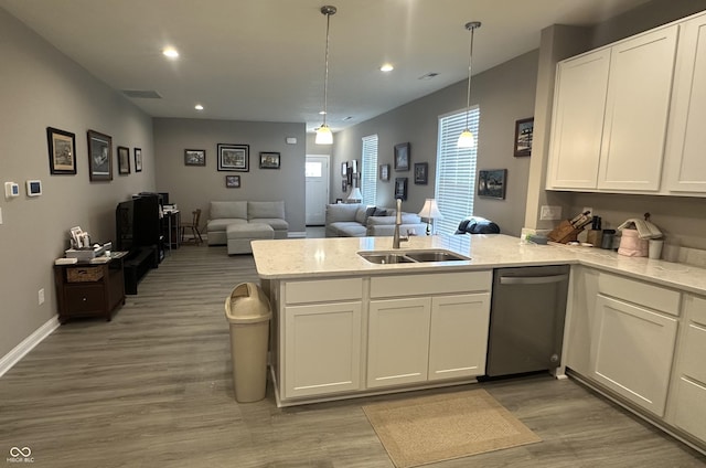 kitchen featuring a peninsula, a sink, white cabinets, stainless steel dishwasher, and open floor plan