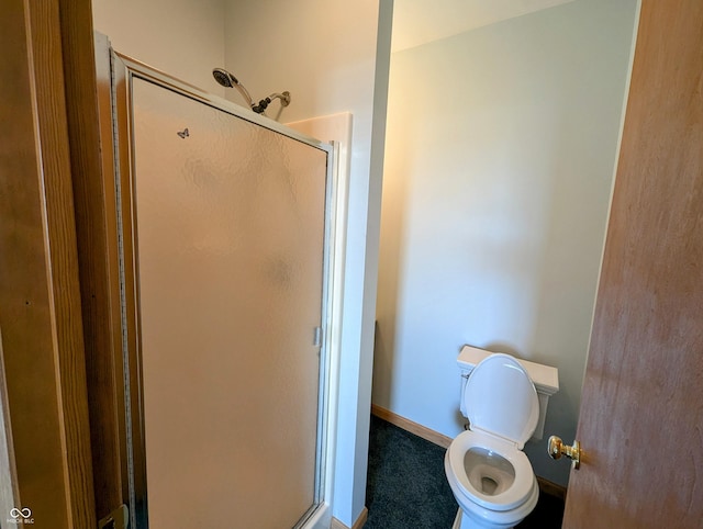 bathroom with toilet, baseboards, and a stall shower