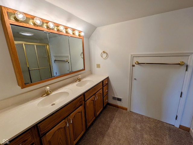 full bathroom featuring a sink, a shower with door, lofted ceiling, and double vanity