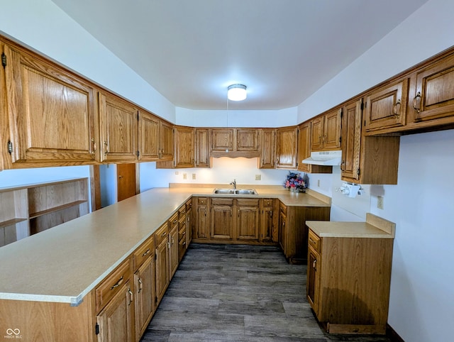 kitchen with a peninsula, a sink, light countertops, under cabinet range hood, and brown cabinets