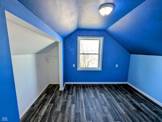 additional living space featuring a textured ceiling, lofted ceiling, baseboards, and wood finished floors