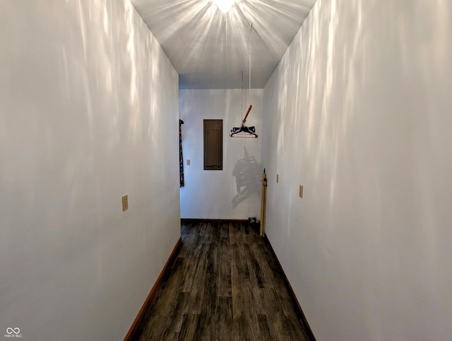 hall with dark wood-type flooring, electric panel, and baseboards