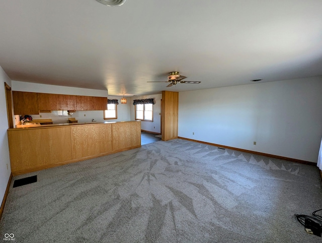 unfurnished living room featuring ceiling fan, baseboards, and carpet floors