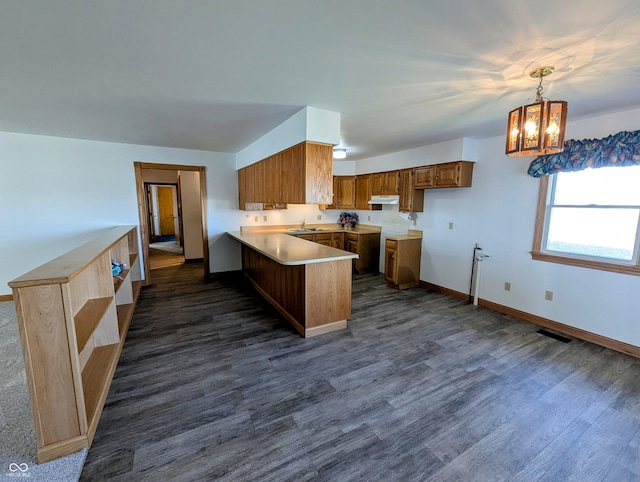 kitchen with visible vents, dark wood-type flooring, under cabinet range hood, a peninsula, and a sink