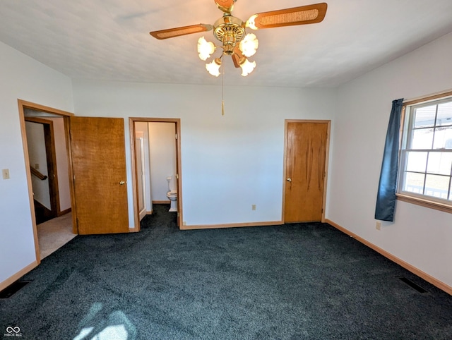 unfurnished bedroom featuring visible vents, baseboards, ensuite bathroom, a ceiling fan, and dark colored carpet