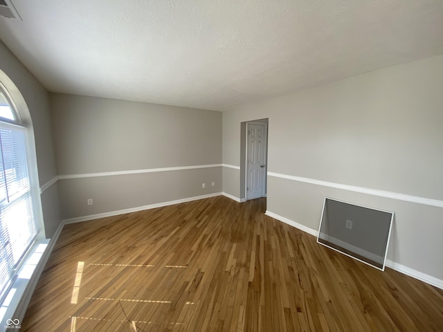 empty room featuring visible vents, wood finished floors, and baseboards