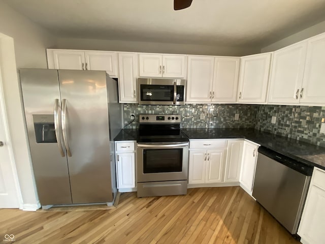 kitchen with light wood-type flooring, stainless steel appliances, tasteful backsplash, and white cabinets