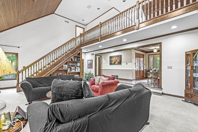 living area with stairway, baseboards, carpet floors, and high vaulted ceiling