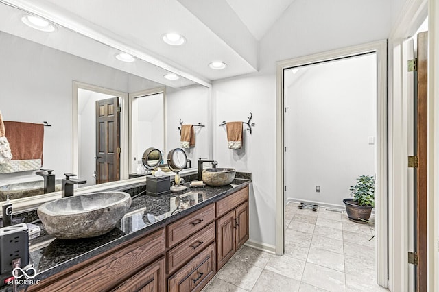 bathroom with double vanity, vaulted ceiling, recessed lighting, and a sink