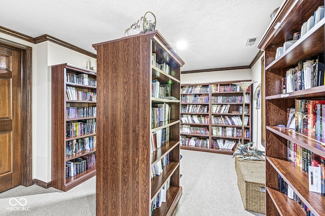 living area with visible vents, carpet floors, ornamental molding, bookshelves, and a textured ceiling