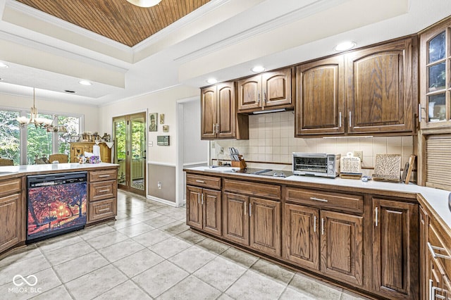 kitchen featuring backsplash, light countertops, a tray ceiling, ornamental molding, and black appliances