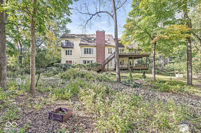 rear view of property with a wooden deck, a chimney, and stairs