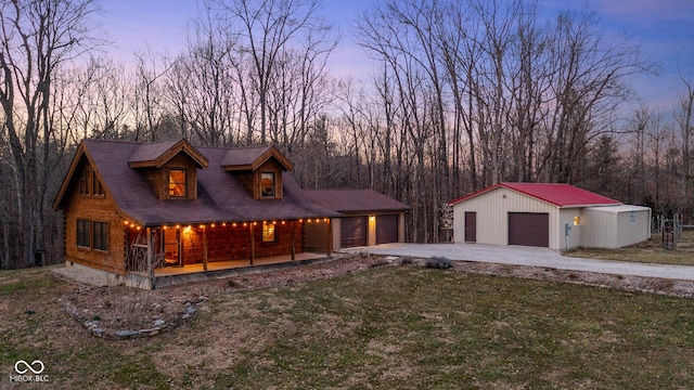 chalet / cabin with covered porch, a lawn, and a garage