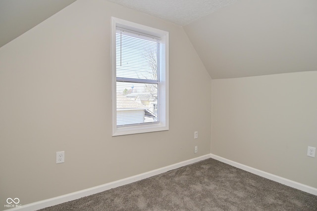 bonus room with baseboards, dark colored carpet, and a textured ceiling