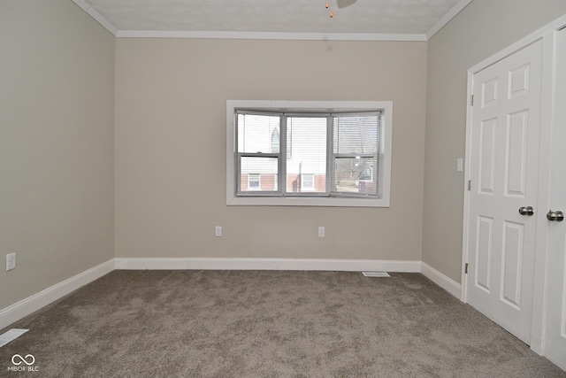 empty room with crown molding, carpet, baseboards, and visible vents