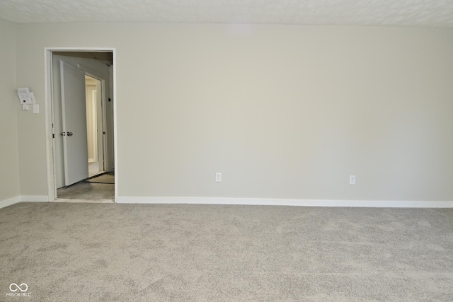 carpeted empty room with baseboards and a textured ceiling