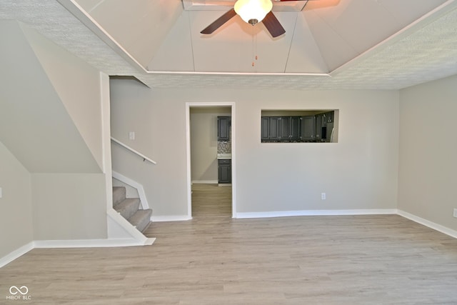 spare room with ceiling fan, stairway, wood finished floors, and vaulted ceiling