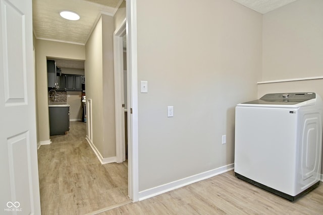 washroom featuring baseboards, laundry area, washer / clothes dryer, ornamental molding, and light wood-type flooring