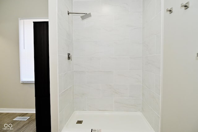 full bathroom featuring baseboards, tiled shower, visible vents, and wood finished floors