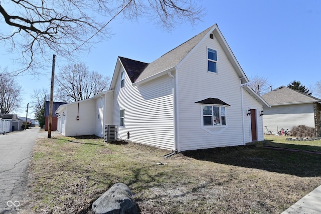 view of side of home with a lawn and central AC