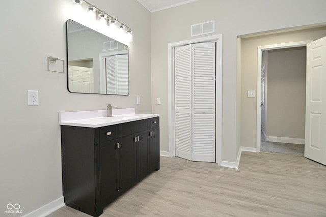 bathroom with visible vents, vanity, baseboards, and wood finished floors