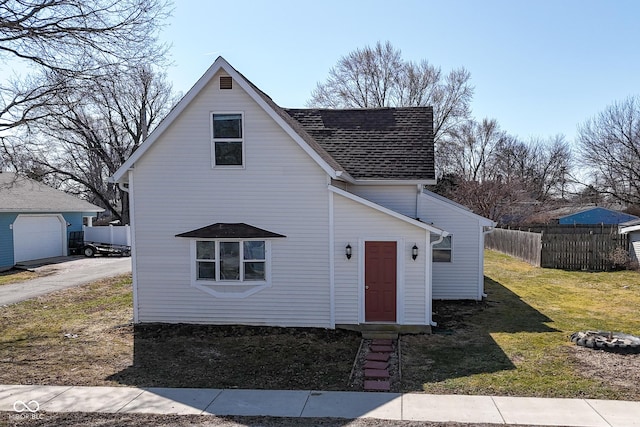 traditional-style home with a shingled roof, a front lawn, and fence