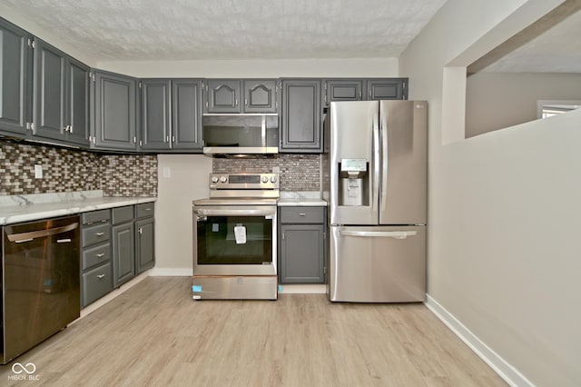 kitchen featuring light wood-type flooring, gray cabinets, stainless steel appliances, and light countertops