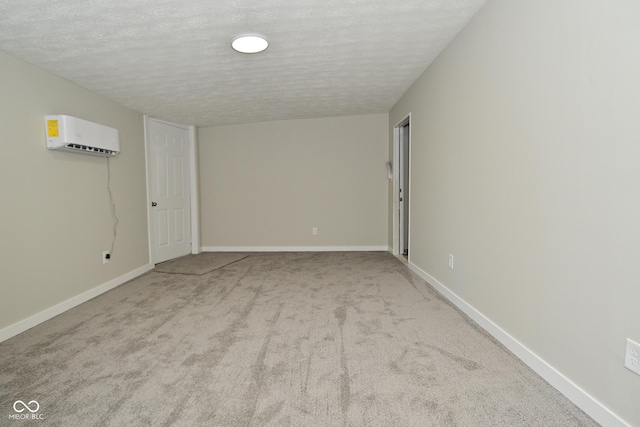 carpeted spare room featuring baseboards, a textured ceiling, and a wall unit AC