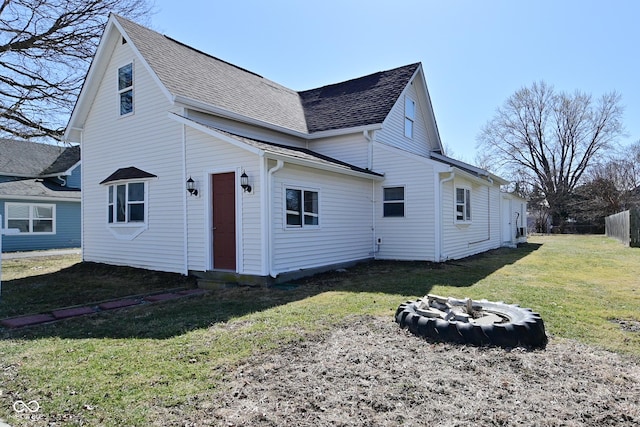 rear view of property with a lawn and roof with shingles