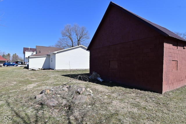 view of side of home with an outdoor structure and a yard