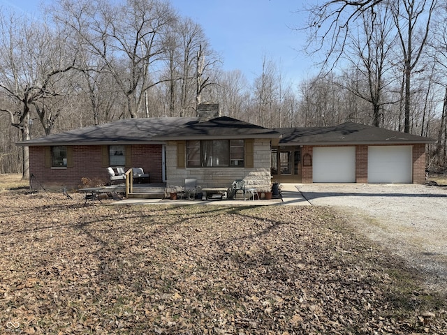 view of front of house featuring a garage, brick siding, driveway, and a chimney