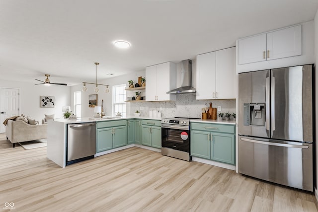 kitchen with open shelves, stainless steel appliances, green cabinets, wall chimney exhaust hood, and open floor plan