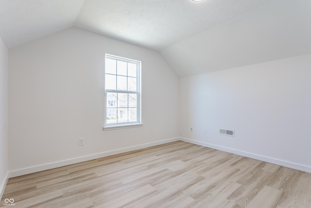 additional living space featuring visible vents, baseboards, lofted ceiling, and wood finished floors