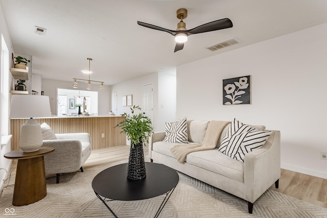 living room with visible vents, a ceiling fan, and light wood finished floors