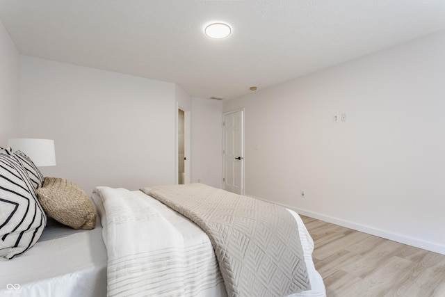 bedroom featuring visible vents, baseboards, and light wood finished floors