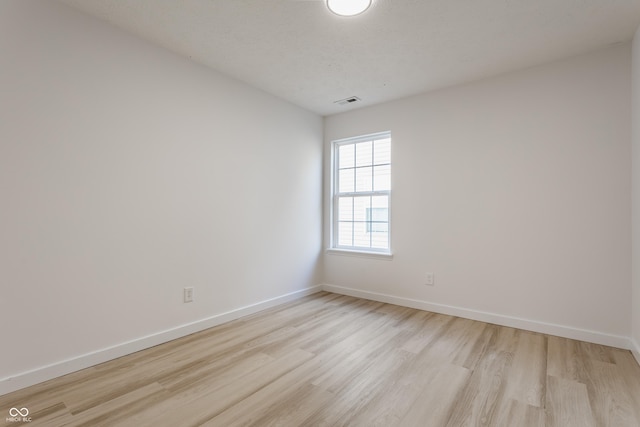 unfurnished room featuring visible vents, light wood-style flooring, and baseboards