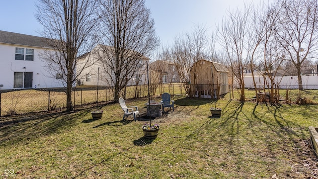 view of yard featuring a barn, a fire pit, fence, and an outdoor structure