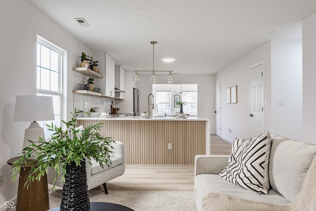 interior space with light wood finished floors, visible vents, and a healthy amount of sunlight