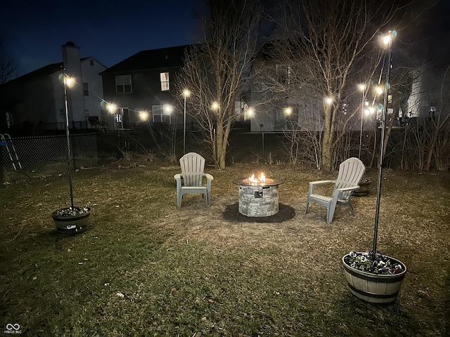 yard at night featuring a fire pit and a fenced backyard