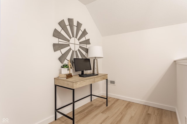 office area featuring light wood-type flooring, baseboards, and vaulted ceiling